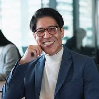 プロフィール写真：眼鏡をかけたスーツ姿の男性が笑顔でこちらを見ている